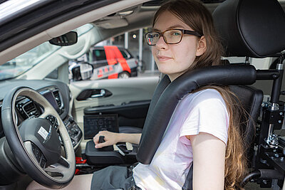 Jana in the driver's seat of her Paravan rental vehicle, secured with a lap belt restraint system