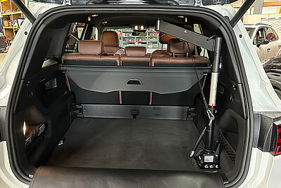 A view into the open trunk of a Mercedes GLB. On the right, there is a loading aid with a cable system for loading and unloading a wheelchair.