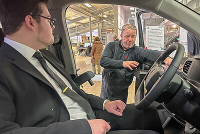 A technician explains the operation of PARAVAN driving aids inside an adapted vehicle for drivers with disabilities.