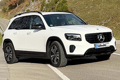 A white Mercedes GLB photographed from the front left at an angle in the sunshine.