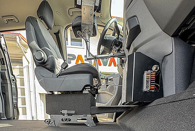 The interior of a vehicle as seen from the floor on the passenger side, where the passenger seat is no longer visible. The driver's seat, however, is not a standard seat but one that can be removed and moved.
