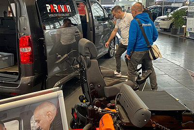 Interested visitors gather information at a converted vehicle on the exhibition stand.