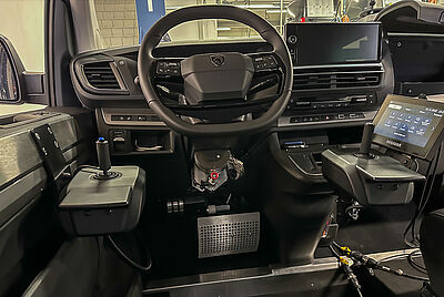 Vehicle cockpit with joystick steering and PARAVAN drive-by-wire technology enabling accessible driving.