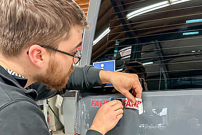 A Paravan employee attaches a red sticker with “novice driver” to the rear of the vehicle.