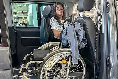 Open side door of a vehicle with a ramp; a wheelchair is positioned inside the cabin behind the driver’s seat.