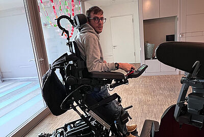 Man using a power wheelchair with head support and adaptive controls – customized solution for enhanced daily mobility.