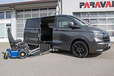 A gray VW New Caravelle with the rear door open, a cassette lift extended, with a wheelchair partially on it.