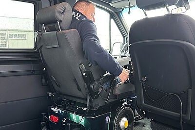 Interior view of a vehicle with an adapted driver’s seat and headrest, showing the driver’s side and dashboard controls.