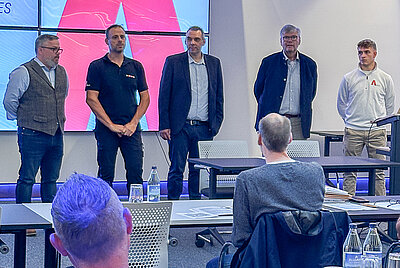Presentation or recognition at Paravan GmbH: four people standing at the front of a seminar room, audience in the foreground.