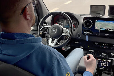 Over-the-shoulder view of a driver looking at the cockpit of a Mercedes van equipped with PARAVAN control systems.