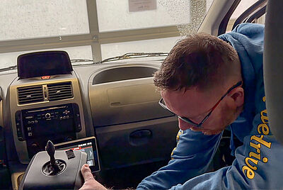 Man inside a vehicle operating an electronic control unit for driving functions next to the driver’s seat.
