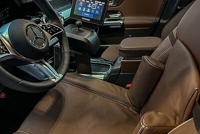 A custom-fitted driver's seat with a custom-made backrest, featuring a joystick control to the right of the steering wheel. The PARAVAN Touch System is also located to the right, behind the joystick.