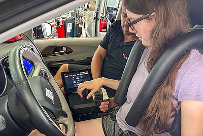 Driving instructor Ralf explains to Jana how to operate her new vehicle.