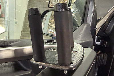 Close-up of a custom vehicle mount with two vertical grips installed on the inside of the driver’s door.