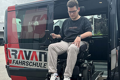 Wheelchair user using a ramp to enter an adapted PARAVAN driving school vehicle.