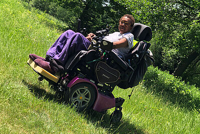 Woman driving a power wheelchair outdoors – active everyday mobility with a PARAVAN wheelchair.