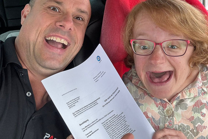 On the right is a beaming man from Paravan GmbH; on the left is a beaming, overjoyed woman. Both are holding up a TÜV certificate to the camera.