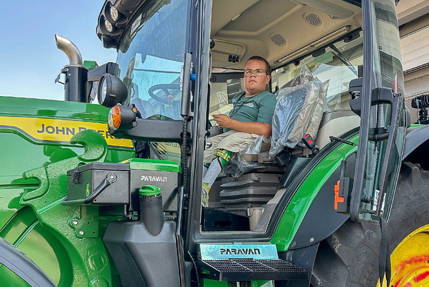 Young man in the cockpit of a John Deere tractor individually adapted by PARAVAN.