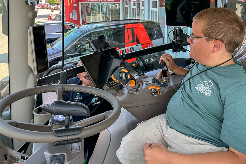Young man operating the converted John Deere tractor using an individually adapted control system.
